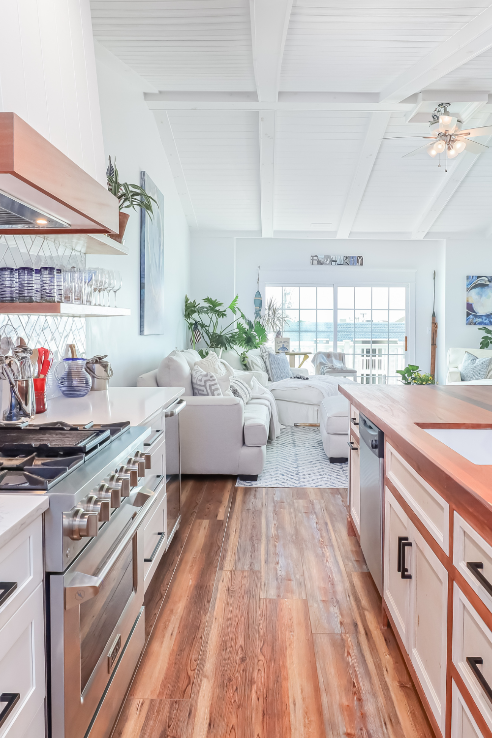 Kitchen and living room combination with white walls and countertops and wooden floor and center island.