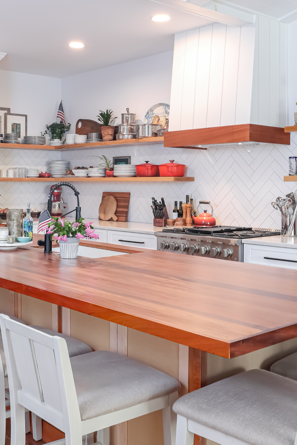 White kitchen cabinets and backsplash with wooden center island.