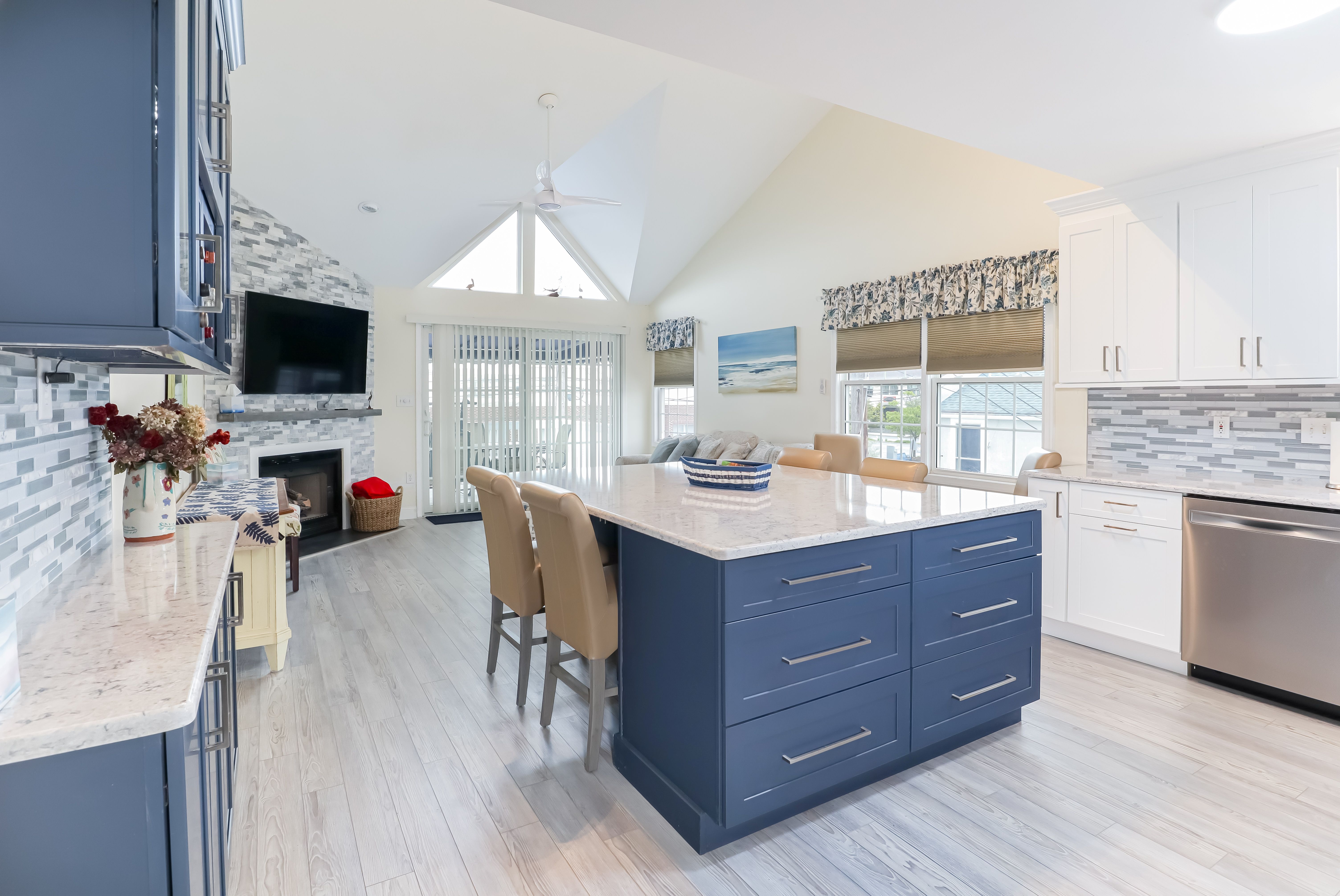 A kitchen with blue cabinets, white countertops, and wood flooring.
