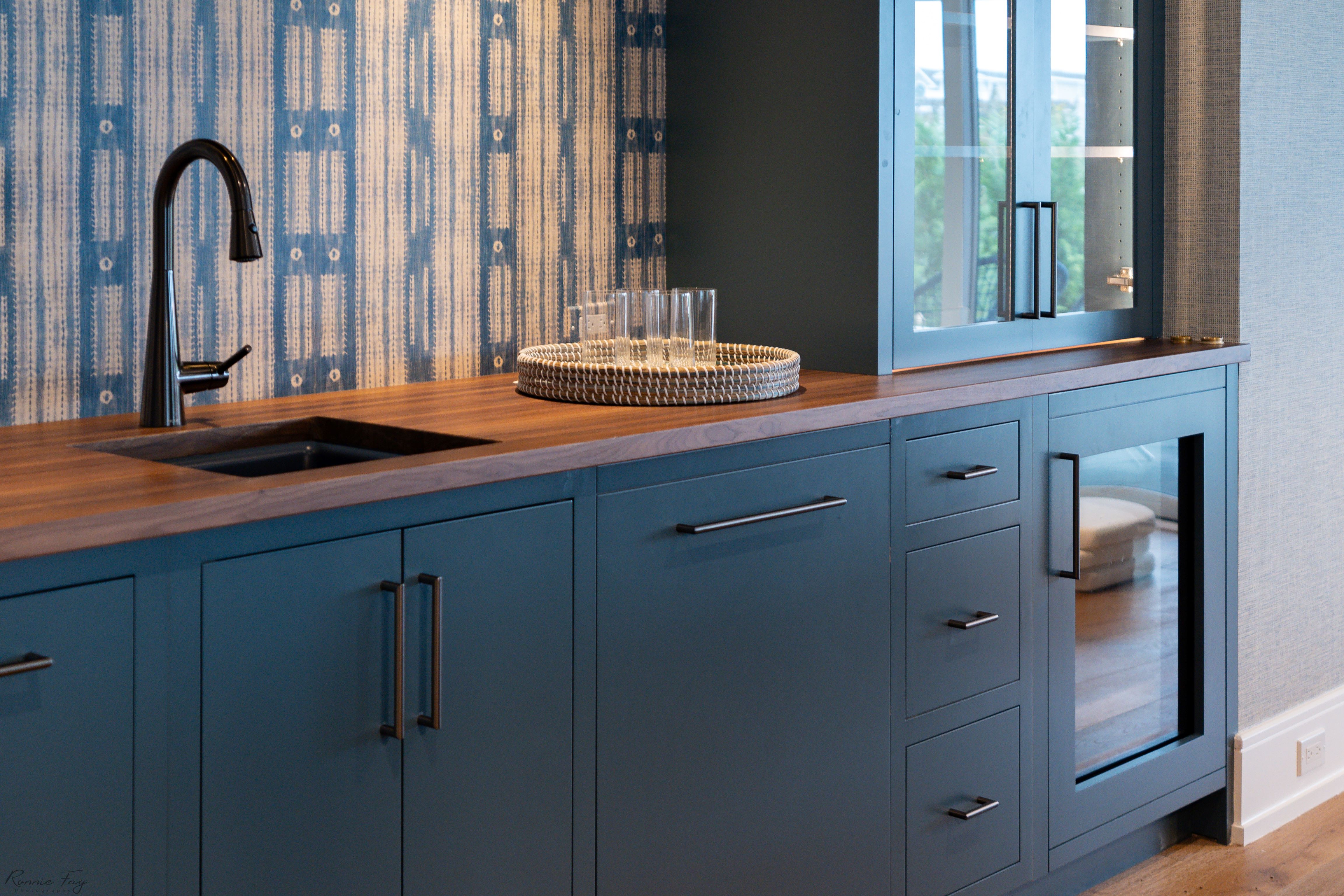 A navy blue cabinet with blue and white striped wallpaper.