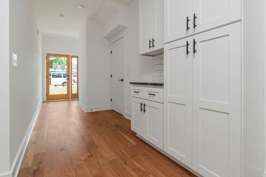 Mud room hallway with floor-to-ceiling white cabinetry and hardwood floors