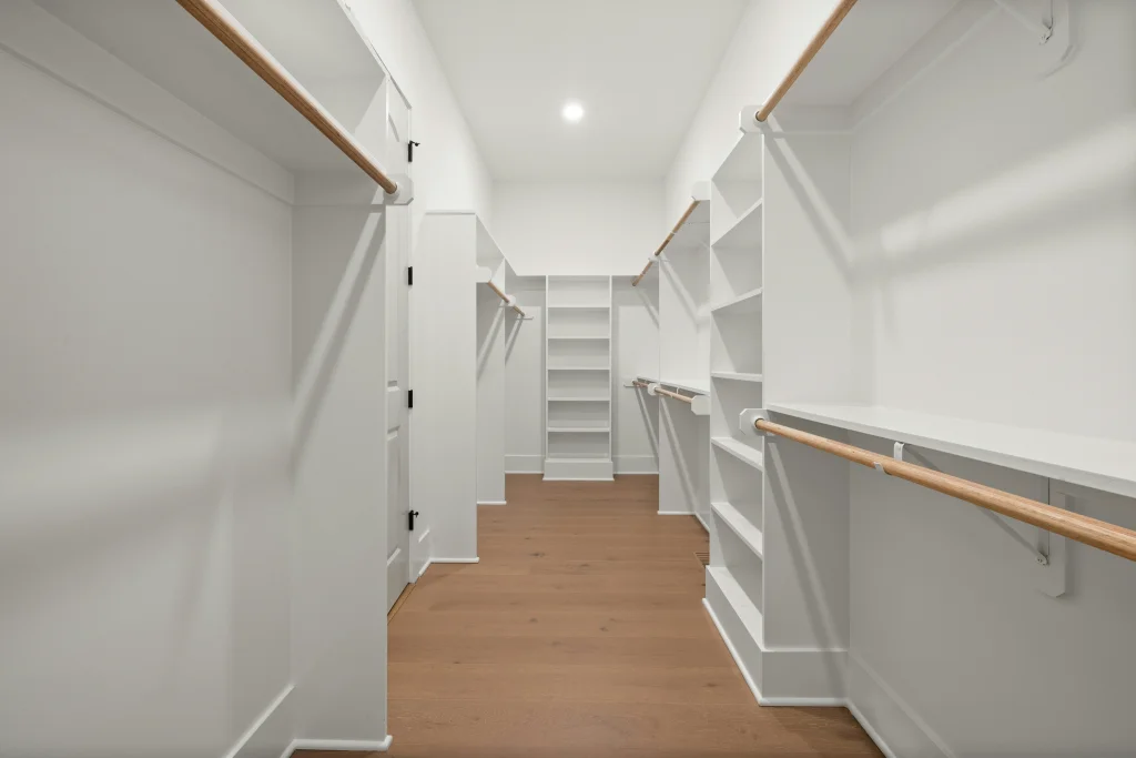 Walk-in closet with hardwood floors and custom hanging space